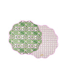 Two scalloped round placemats with a pink border, displayed overlapping on a white background. One placemat features a green and white citrus slice pattern, while the other shows a white lattice pattern on a light pink background.
