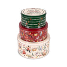 Three stacked round metal tins with Christmas-themed illustrated labels on a plain white background. The top tin is dark green with red and gold; the middle tin is red with multicolor holiday figures; the bottom tin is cream with festive illustrations.