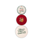 Three round Christmas-themed tin lids stacked vertically on a white background. The top sticker is cream with green and red text reading 'On the First Day Christmas'
