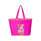 A bright pink tote bag with a vertically pleated texture, featuring a floral pocket on the front and striped trim along the handles and edges, set against a plain white background.