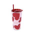 Pink tumbler with red heart patterns and a red straw on a white background