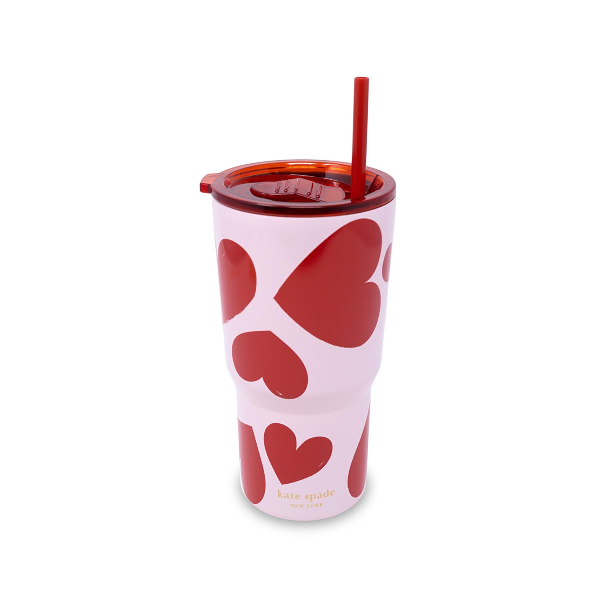 Pink tumbler with red heart patterns and a straw on a white background