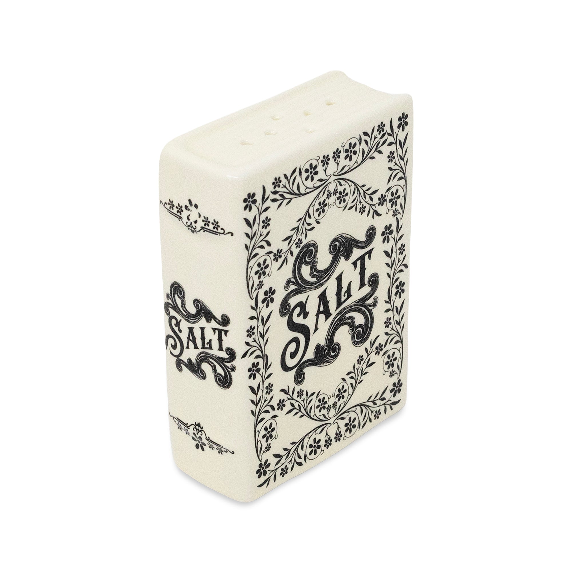 An off-white ceramic salt and pepper shaker designed like a vintage book, featuring black floral borders and the word 'SALT' printed on the cover, set against a plain white background.
