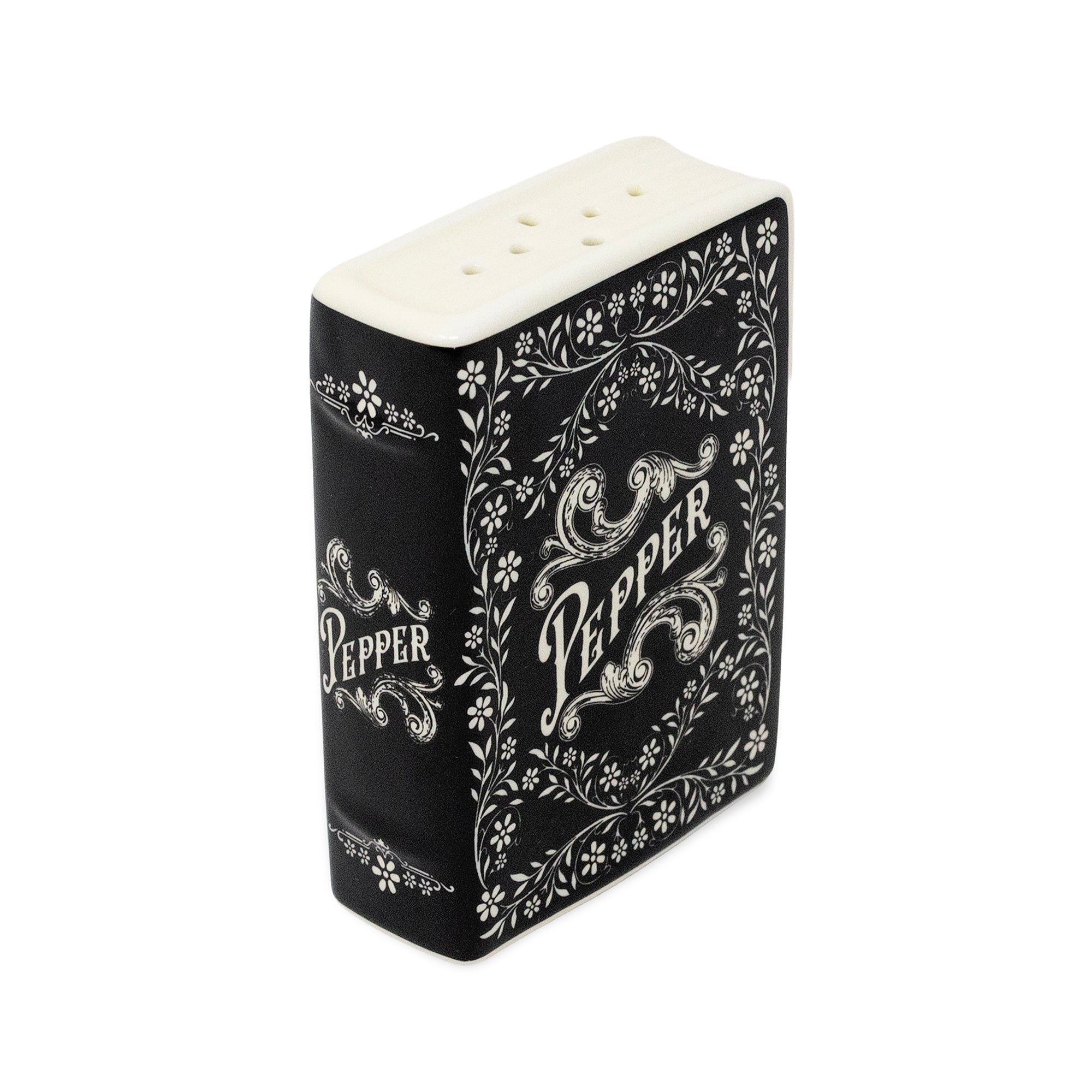 A decorative black and white pepper shaker styled like a vintage book cover, featuring ornate white floral scrollwork and the word 'Pepper' on a white top with small holes.