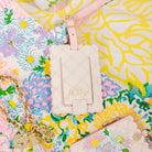 Pink luggage tag with 'Lilly Pulitzer' branding on a colorful floral background