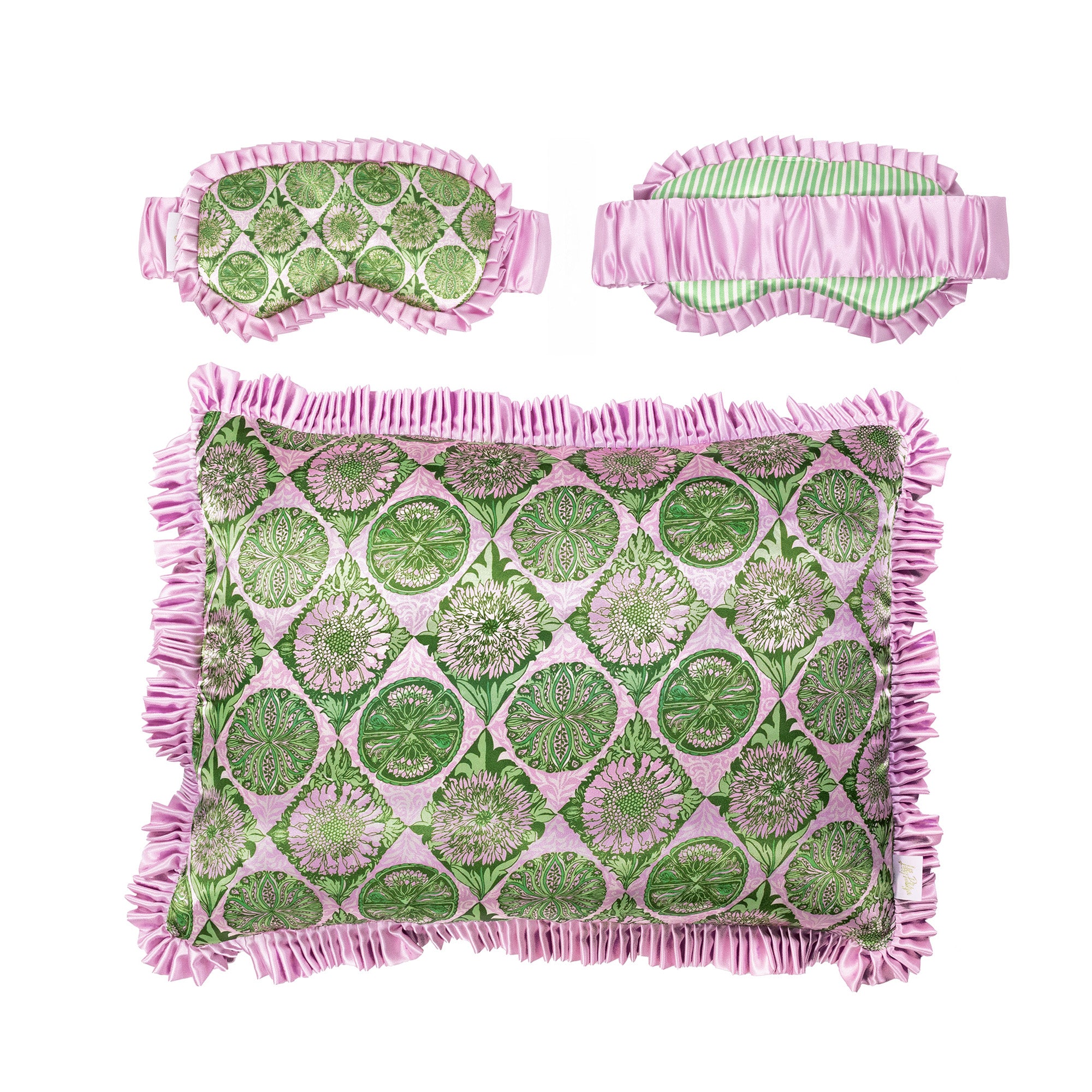 A decorative throw pillowcase with a pink and green botanical pattern and fringed edges, shown against a plain white background with matching eye mask