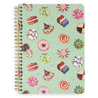 A spiral-bound notebook with a light mint green cover decorated with a colorful pattern of sweets, flowers, and cookies. The notebook has a gold-tone spiral binding on the left side and is photographed against a plain white background.