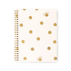 A spiral-bound notebook with a cream-colored cover decorated with scattered gold polka dots and small gold script initials, shown on a plain white background.