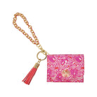 A pink patterned wallet with a gold chain strap, gold ring, and a red and pink tassel, shown on a plain white background.