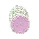 A close-up of a Lilly Pulitzer tumbler showing the bottom, featuring a light pink lid with the brand name embossed, and a white ceramic body decorated with a green and white floral pattern.