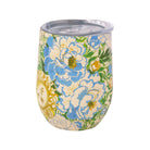A stemless insulated tumbler with a clear lid, decorated with a colorful floral and sun pattern on a cream background. The design features large blue and white flowers with green leaves and yellow-gold sun motifs.