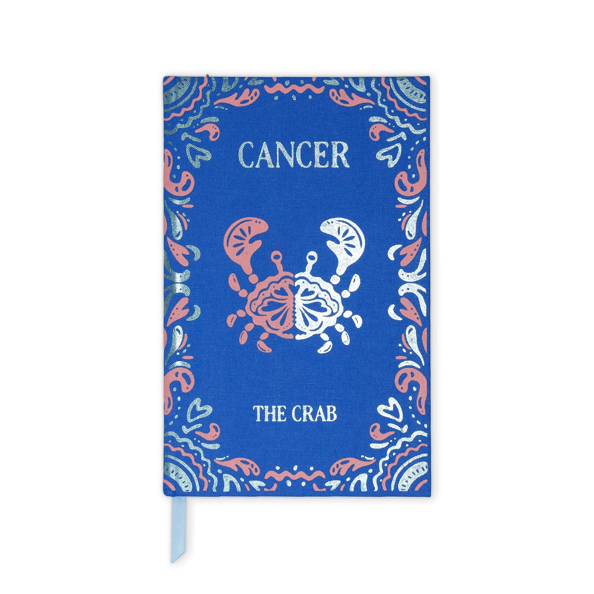 A blue hardcover journal or notebook featuring a zodiac design for Cancer 'The Crab'. The cover has a blue linen texture background with a coral pink and white crab illustration in the center, surrounded by a decorative paisley border.