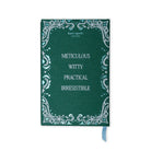 A Kate Spade New York notebook in deep teal green with a silver filigree border and the words 'Meticulous Witty Practical Irresistible' printed in silver. A light blue ribbon bookmark is visible at the bottom right, set against a plain white background.