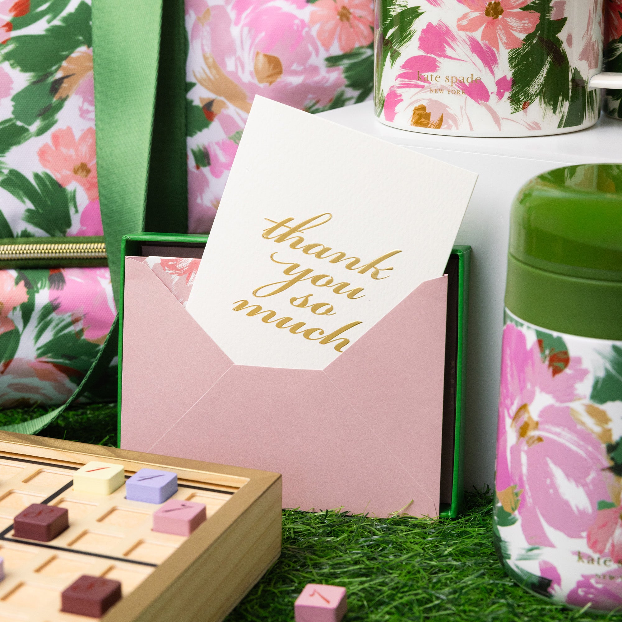 Floral-themed stationery set with a card and mug on a grass-like surface