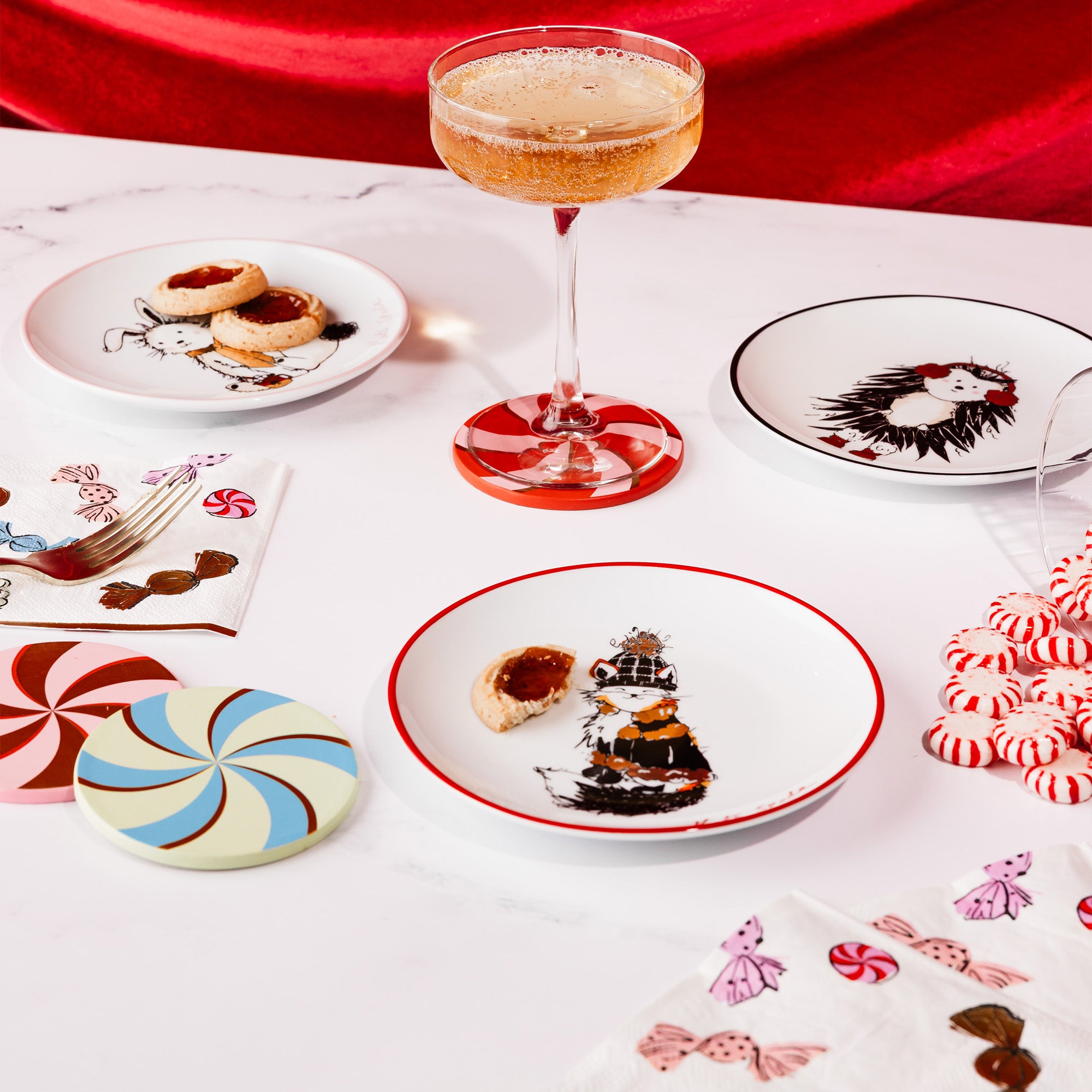 ceramic plates scattered on a table setting with coupe drink, cocktail napkins and leatherette candy coasters