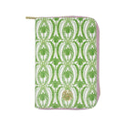 A zip-around jewelry folio with a green and white palm tree pattern, featuring a light pink border and a gold-tone circular logo medallion on the front.