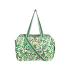 A green and white botanical print duffel bag with green and white striped handles and a matching diagonal shoulder strap, featuring a gold-tone metal brand plaque on the front.