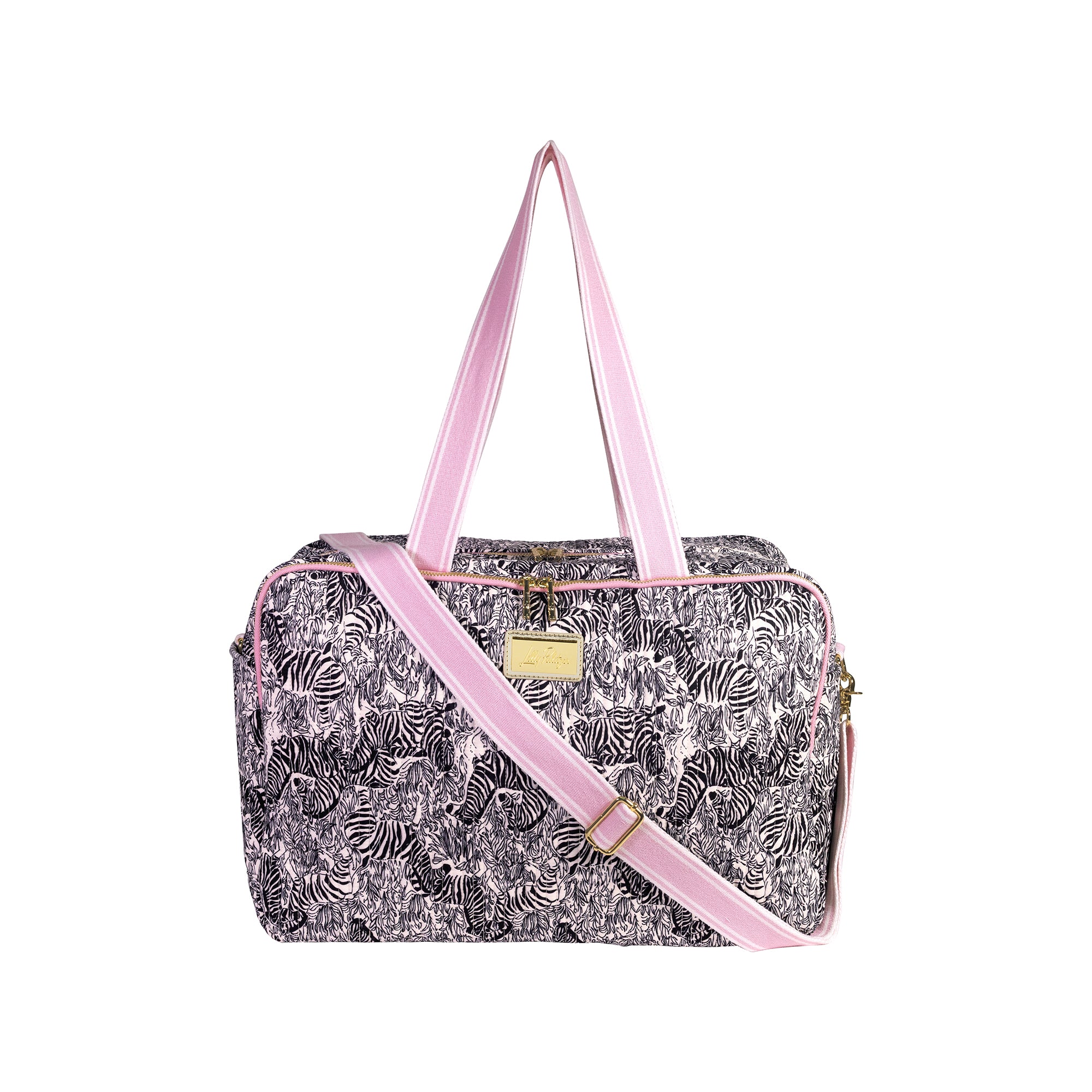 A rectangular duffel bag with a black and white tropical leaf pattern, featuring light pink handles and a matching pink adjustable shoulder strap, with a small gold-tone metal plaque on the front.