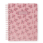A pink spiral-bound planner with a delicate pink and red floral pattern, featuring a central label that reads 'PLANNER' and an elastic closure band.