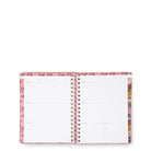 An open spiral-bound planner with a pink floral patterned cover and blank white pages, photographed on a plain white background.