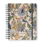 A spiral-bound planner with a beige cover decorated with an intricate vintage-style floral and bird pattern in blue, yellow, green, and pink. The word 'PLANNER' is printed near the bottom center.