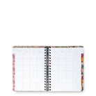 An open spiral-bound planner or agenda with a floral patterned cover and white interior pages, photographed on a plain white background.