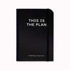 A black hardcover planner with white text reading 'THIS IS THE PLAN' and a smaller phrase near the bottom, shown on a plain light background.