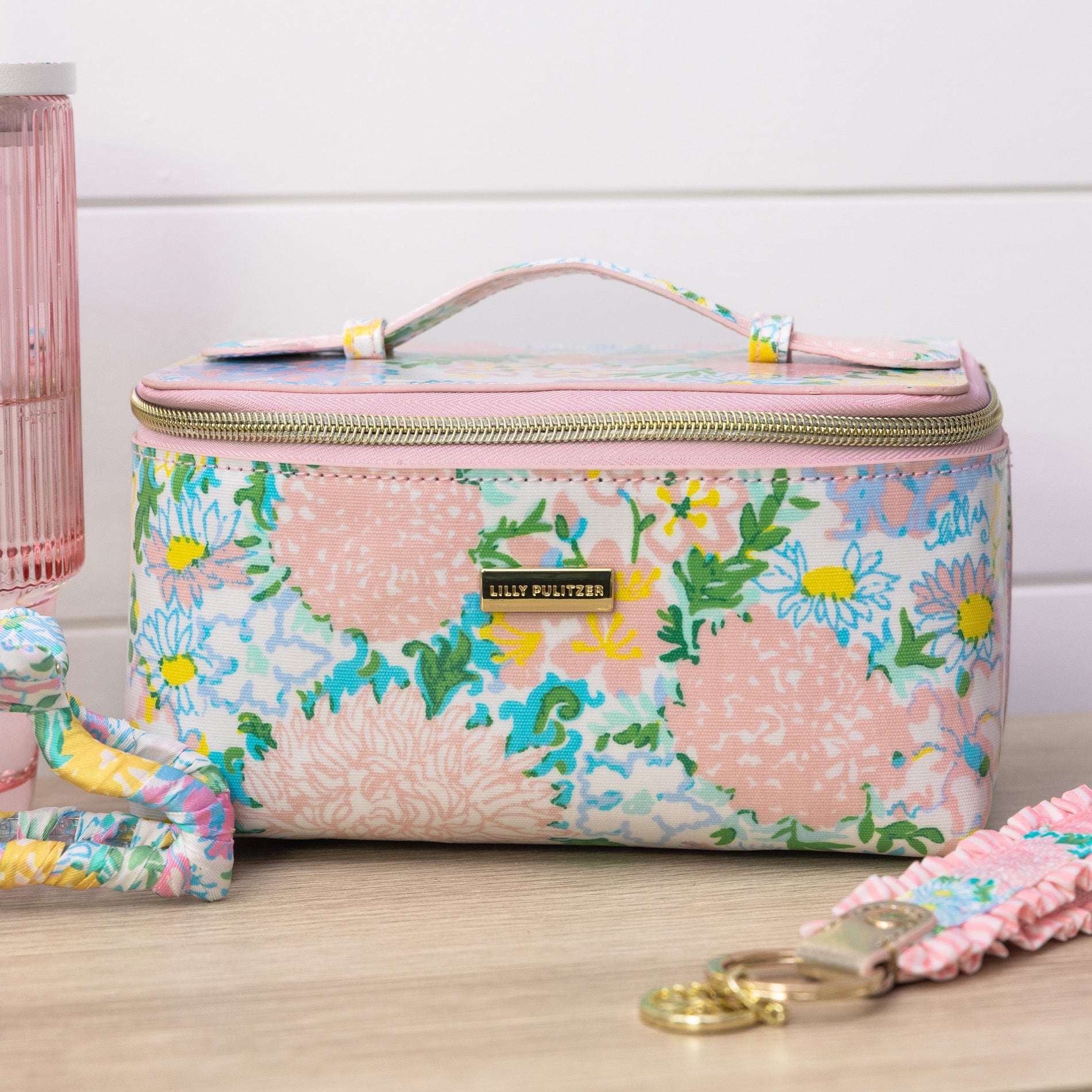 Floral patterned vanity case with pink handle on a wooden surface