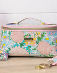 Floral patterned vanity case with pink handle on a wooden surface