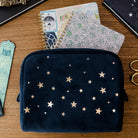Navy pouch with star pattern on a wooden surface with notebooks and scissors.