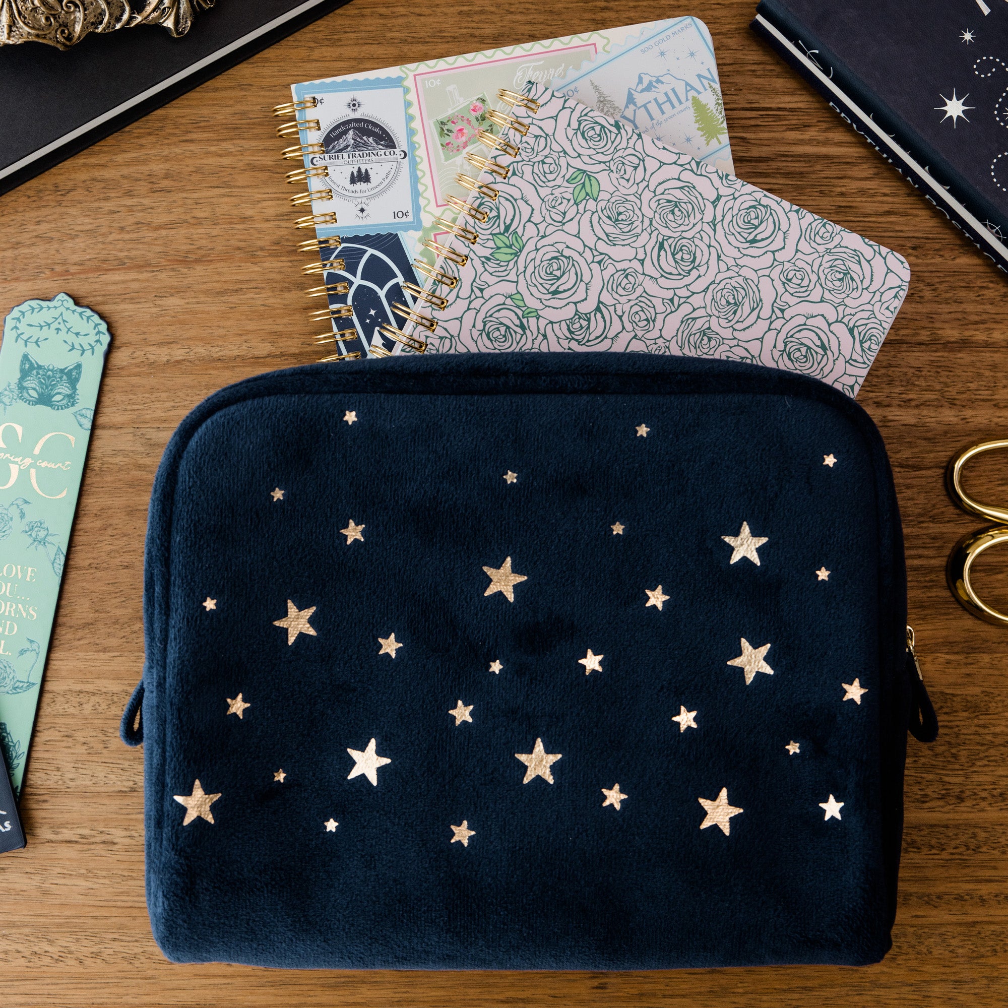 Navy pouch with star pattern on a wooden surface with notebooks and scissors.