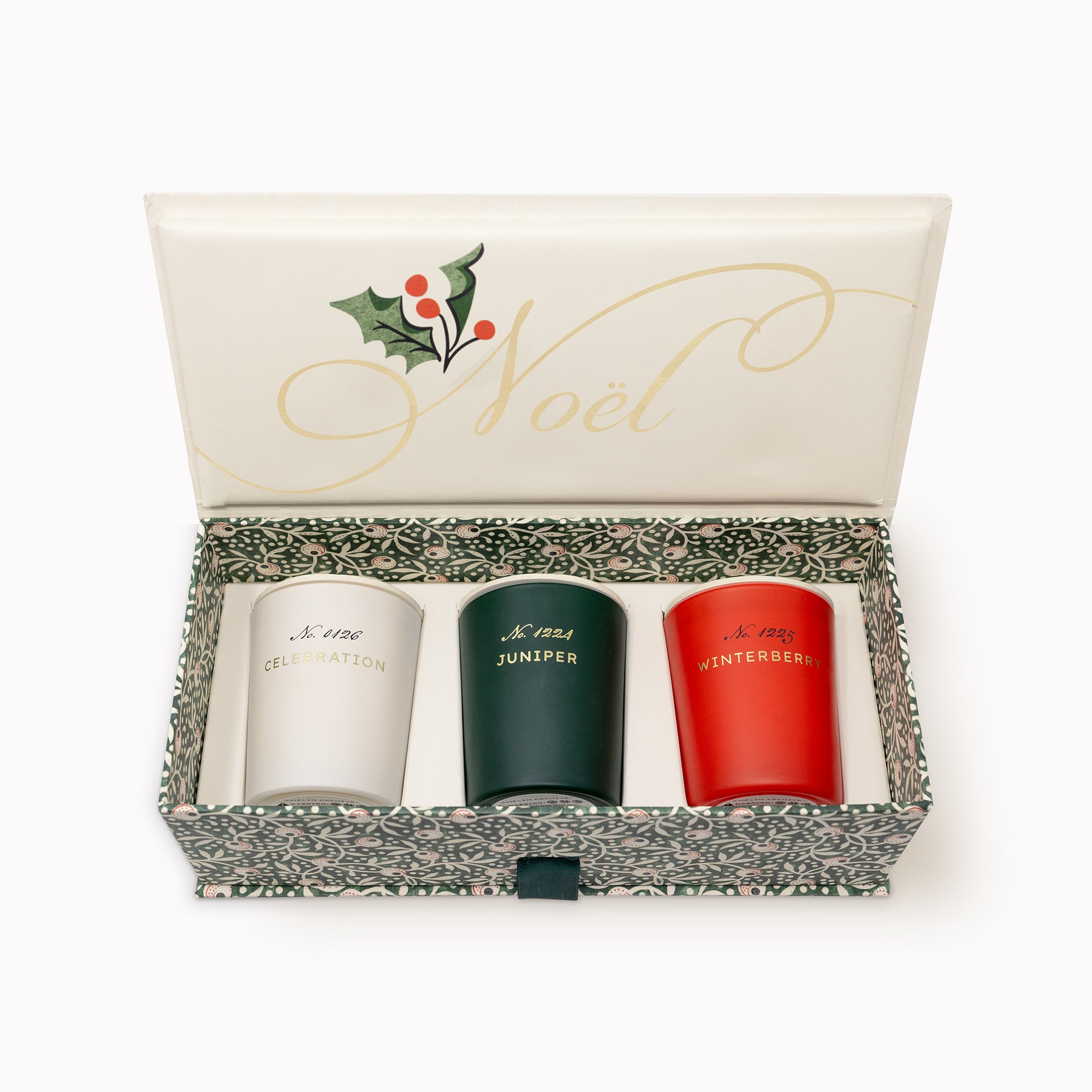 An open Christmas-themed gift box containing three small insulated tumblers. The cream-colored lid features gold cursive writing reading 'Noël' and a holly graphic.