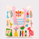 cream tote bag with colorful icon graphic that says 'i'd rather be home reading'