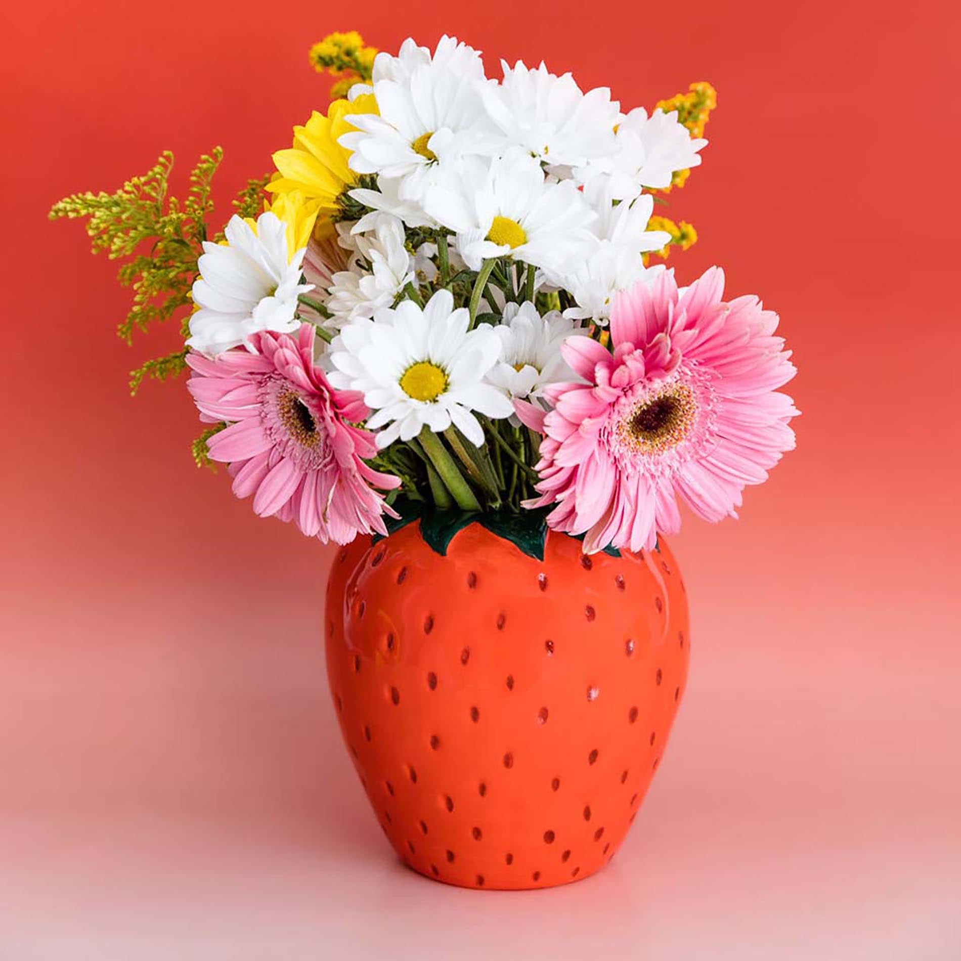 Strawberry-shaped vase with flowers on a gradient background