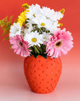 Strawberry-shaped vase with flowers on a gradient background