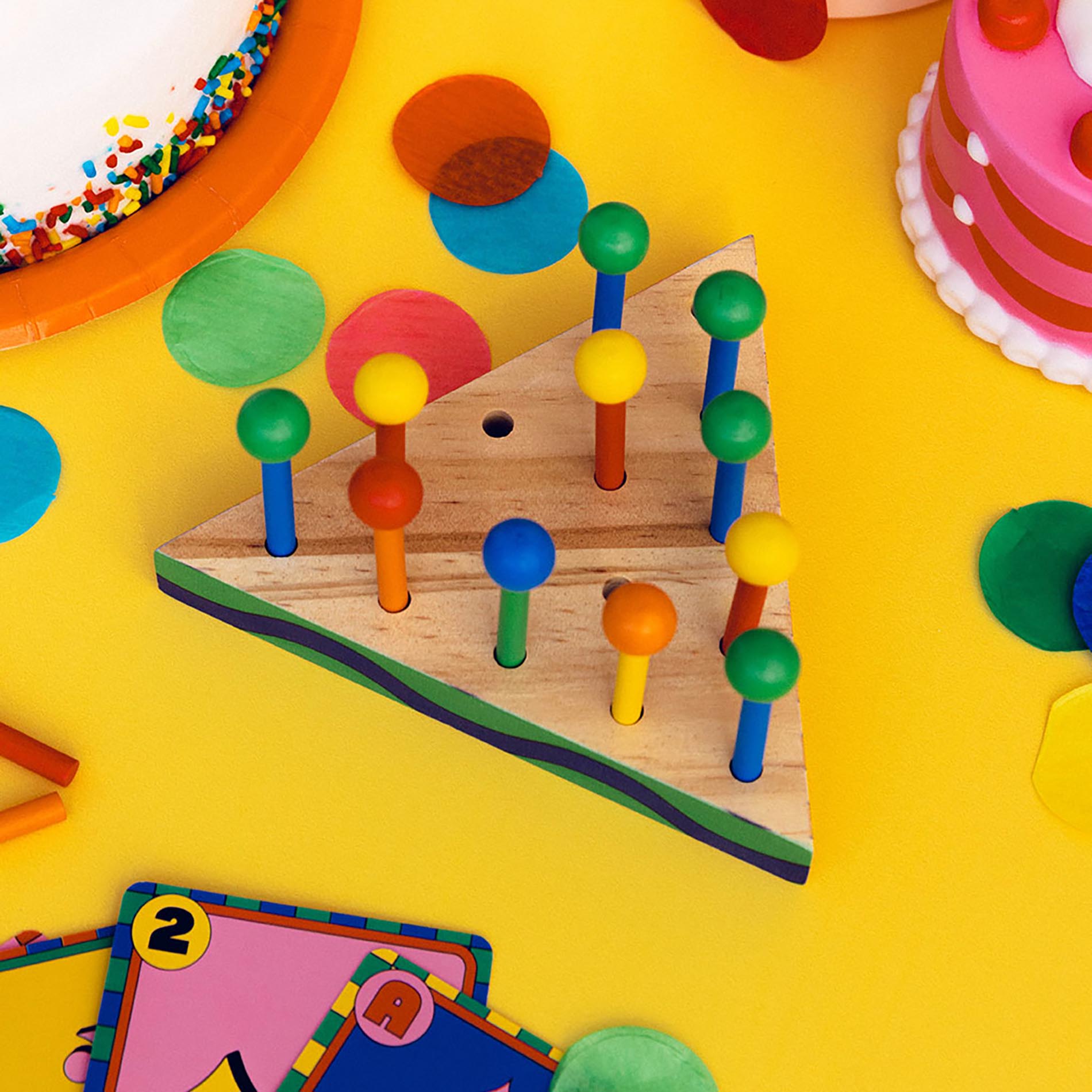 Colorful wooden peg puzzle on a yellow surface with toys around