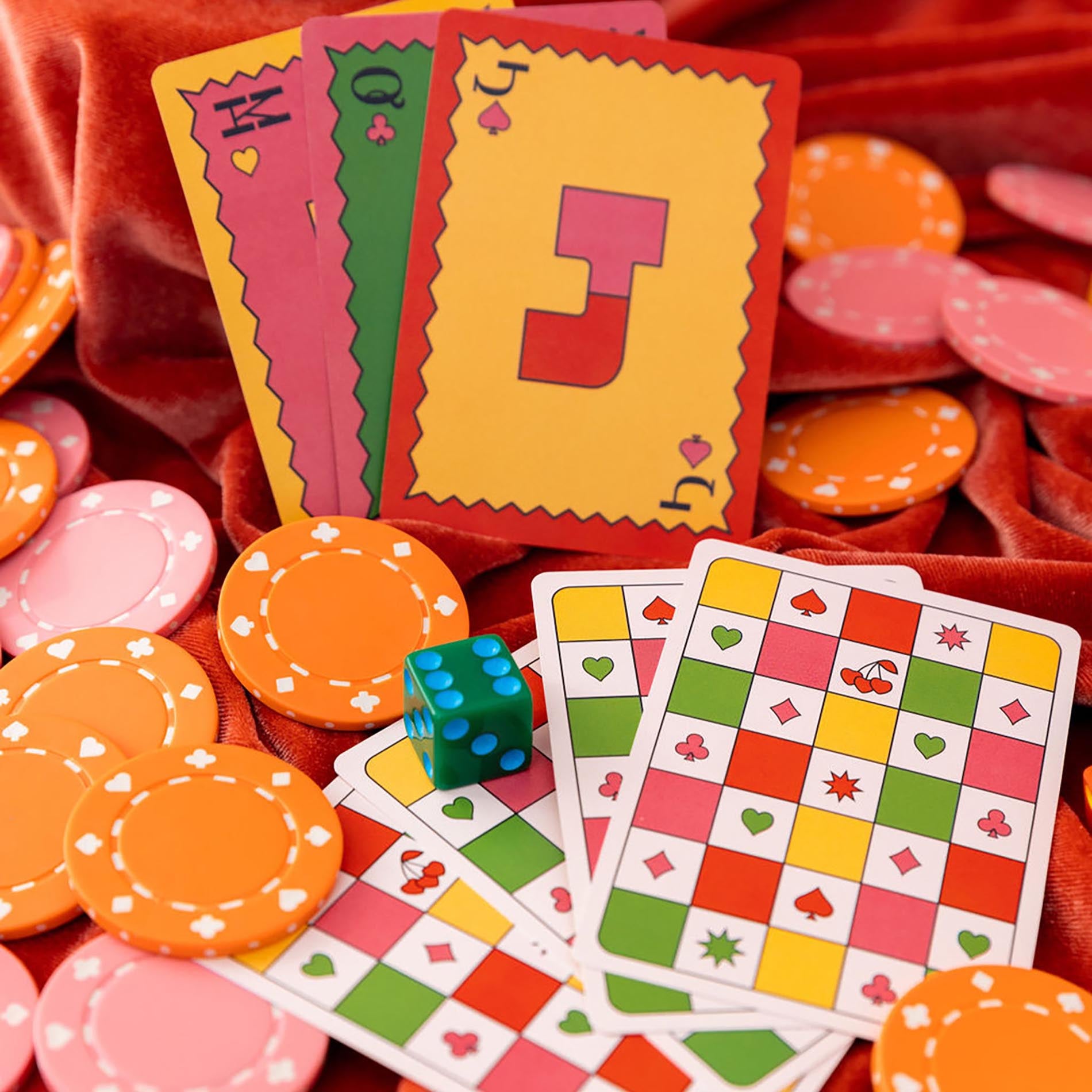 Colorful playing cards and poker chips on a red fabric background