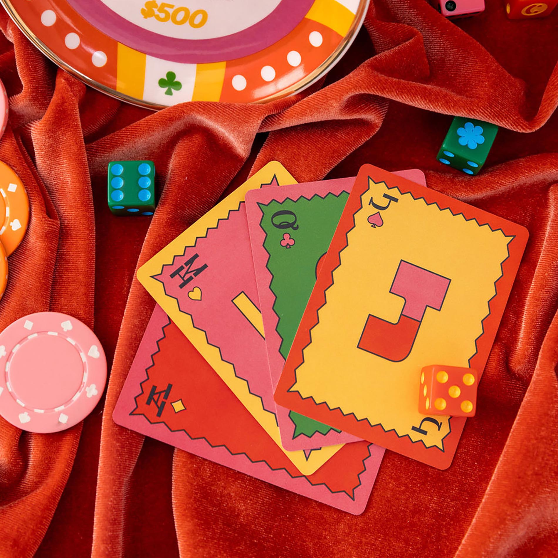 Colorful playing cards and poker chips on a red fabric background
