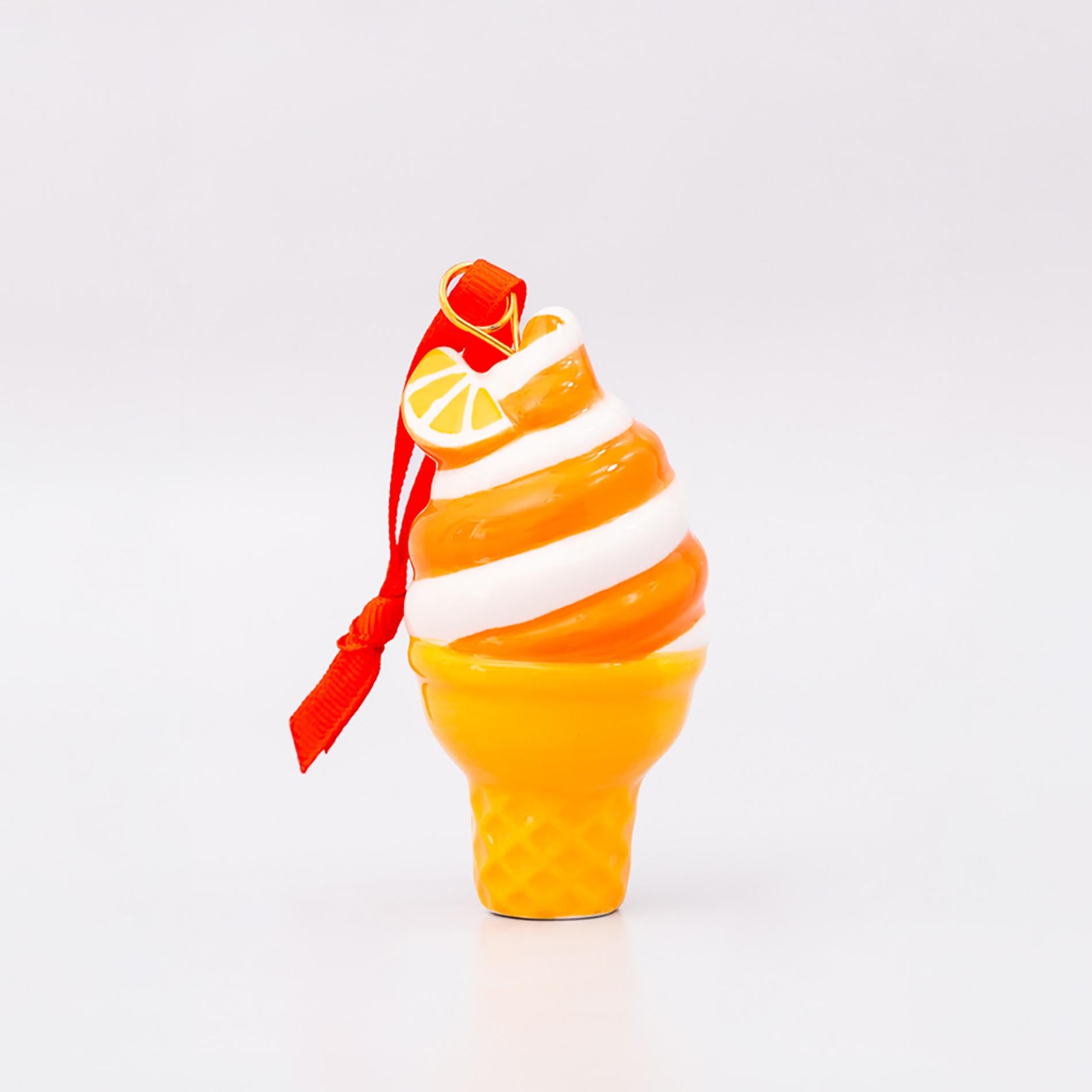Decorative ice cream cone ornament with orange and white swirls on a white background