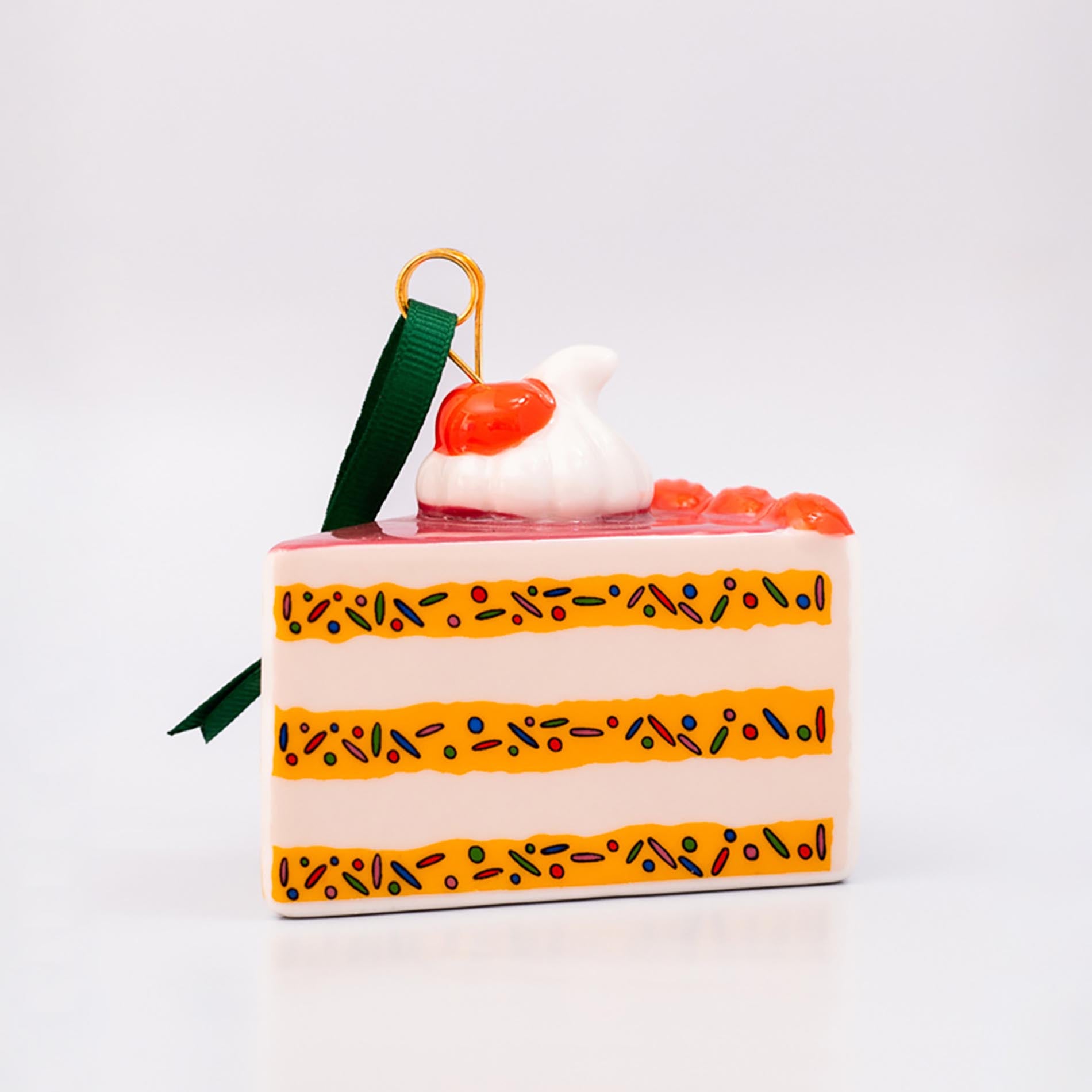 Decorative cake-shaped ornament with a cherry on top against a white background