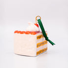Small cake-shaped ornament with a green ribbon on a white background