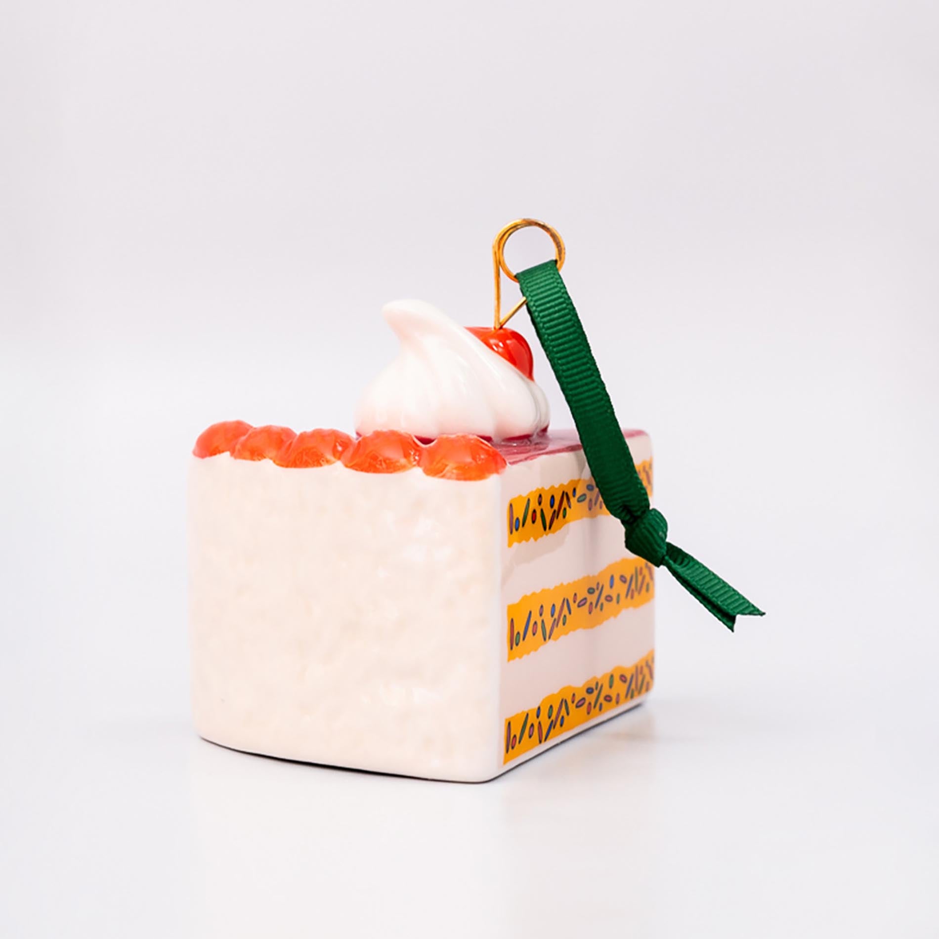 Small cake-shaped ornament with a green ribbon on a white background