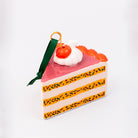 Cake slice ornament with cherry on top against a white background