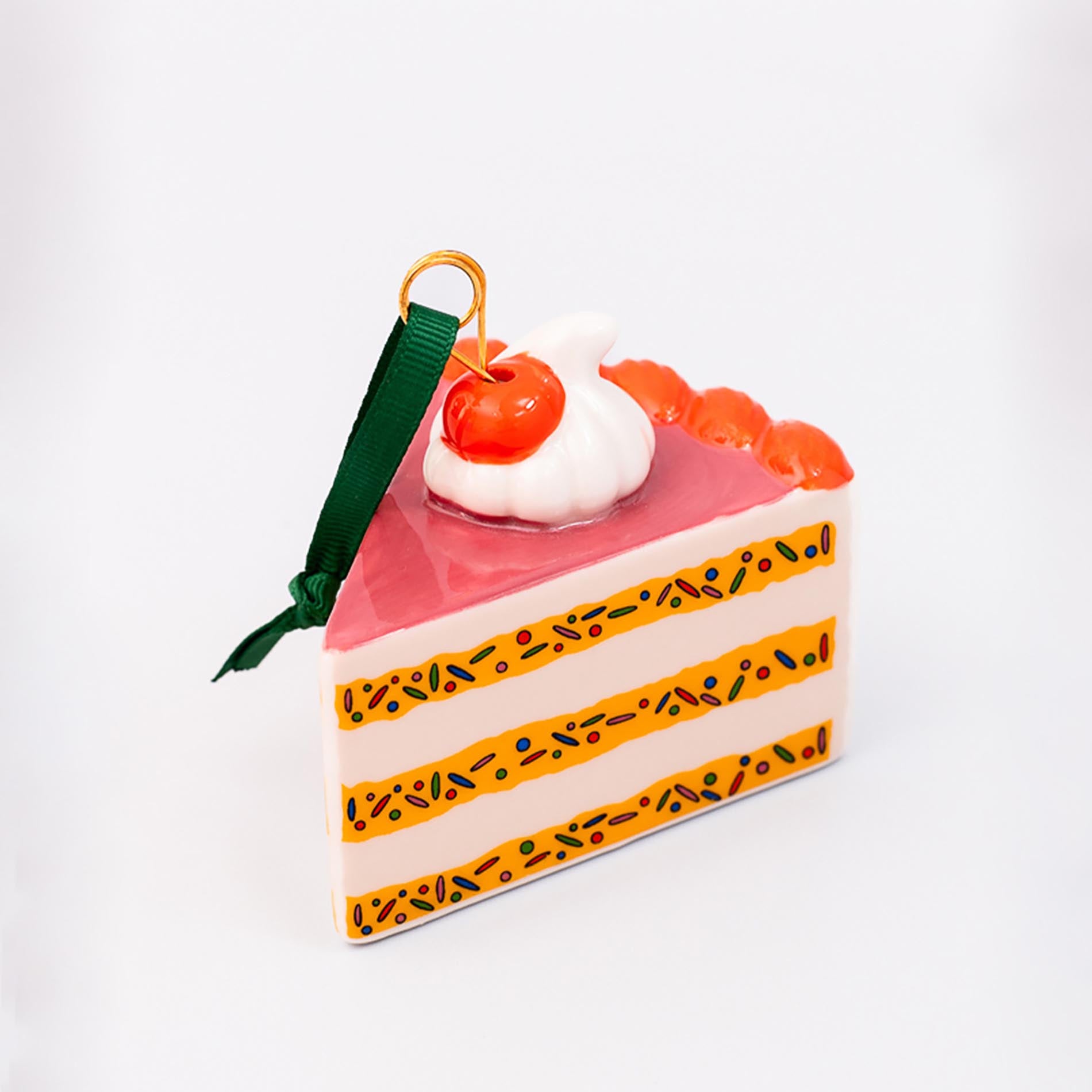 Cake slice ornament with cherry on top against a white background