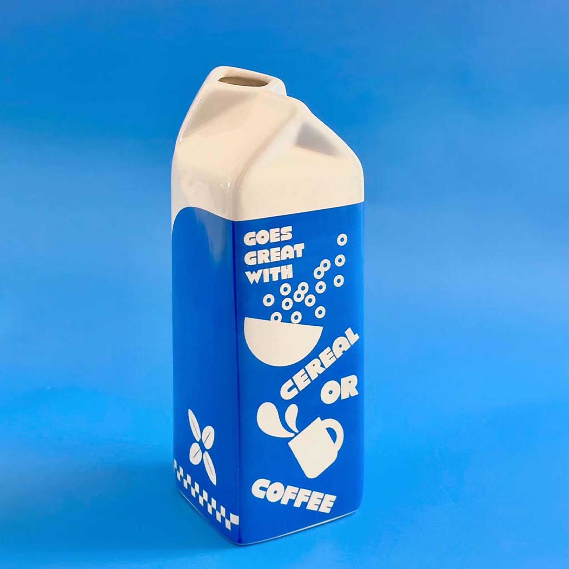 Blue and white milk carton-shaped vase on a blue background
