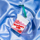 Strawberry milk carton-shaped ornament on a blue satin background