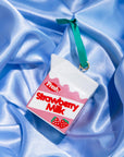 Strawberry milk carton-shaped ornament on a blue satin background