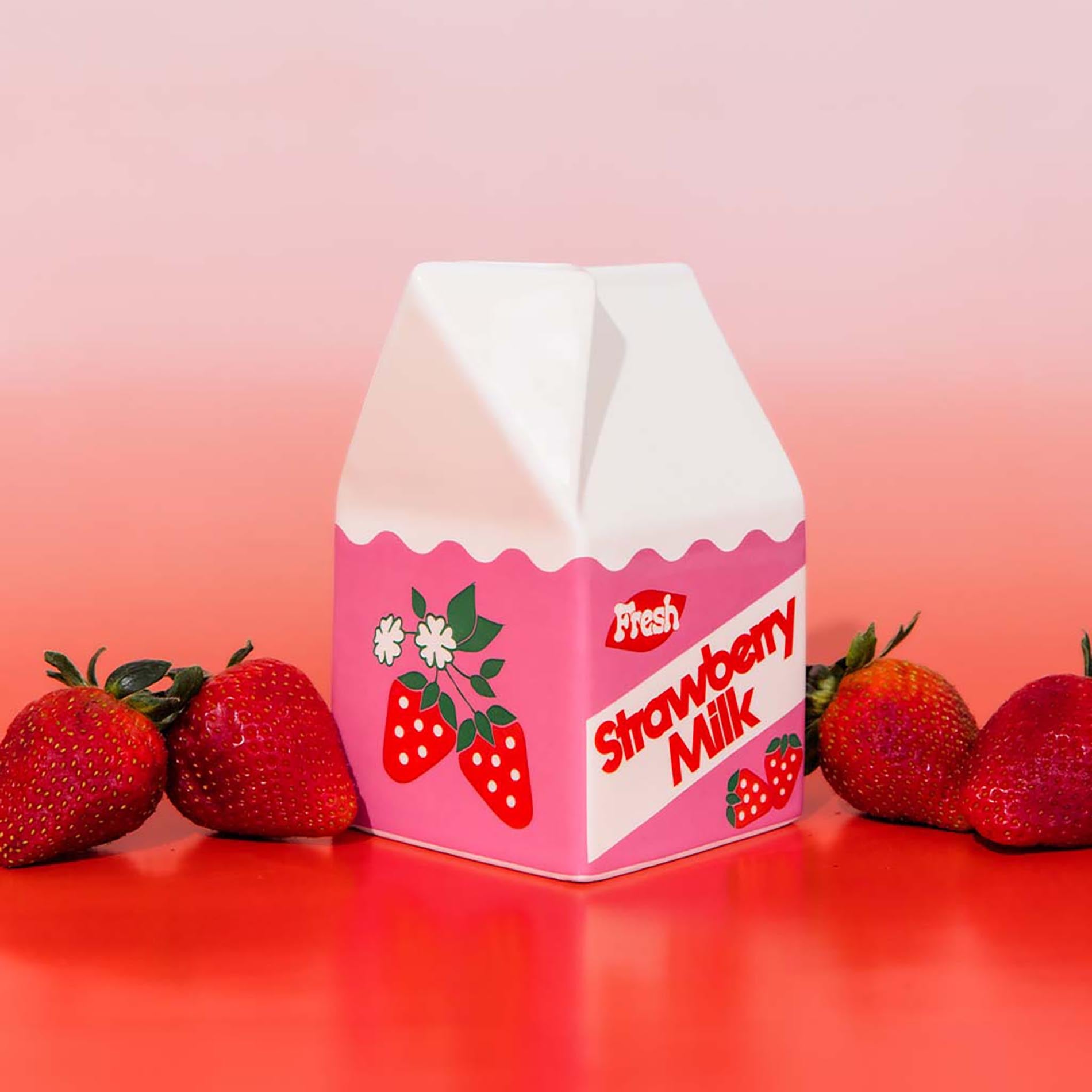 Pink strawberry milk carton with strawberries on a gradient background