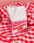 Carton of strawberry milk vase on a red and white checkered tablecloth