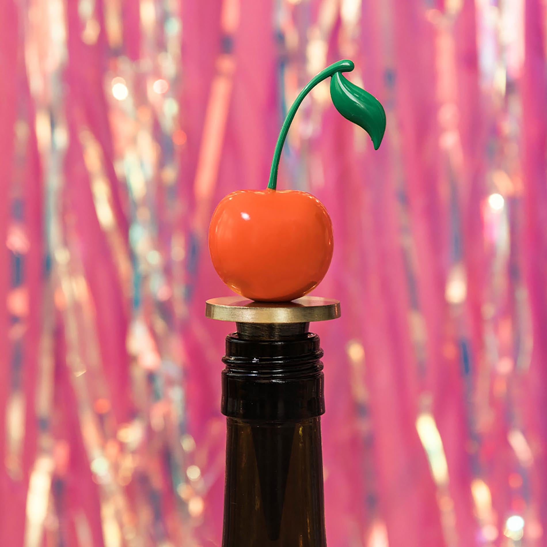 Cherry-shaped bottle stopper on a bottle with a colorful, blurred background